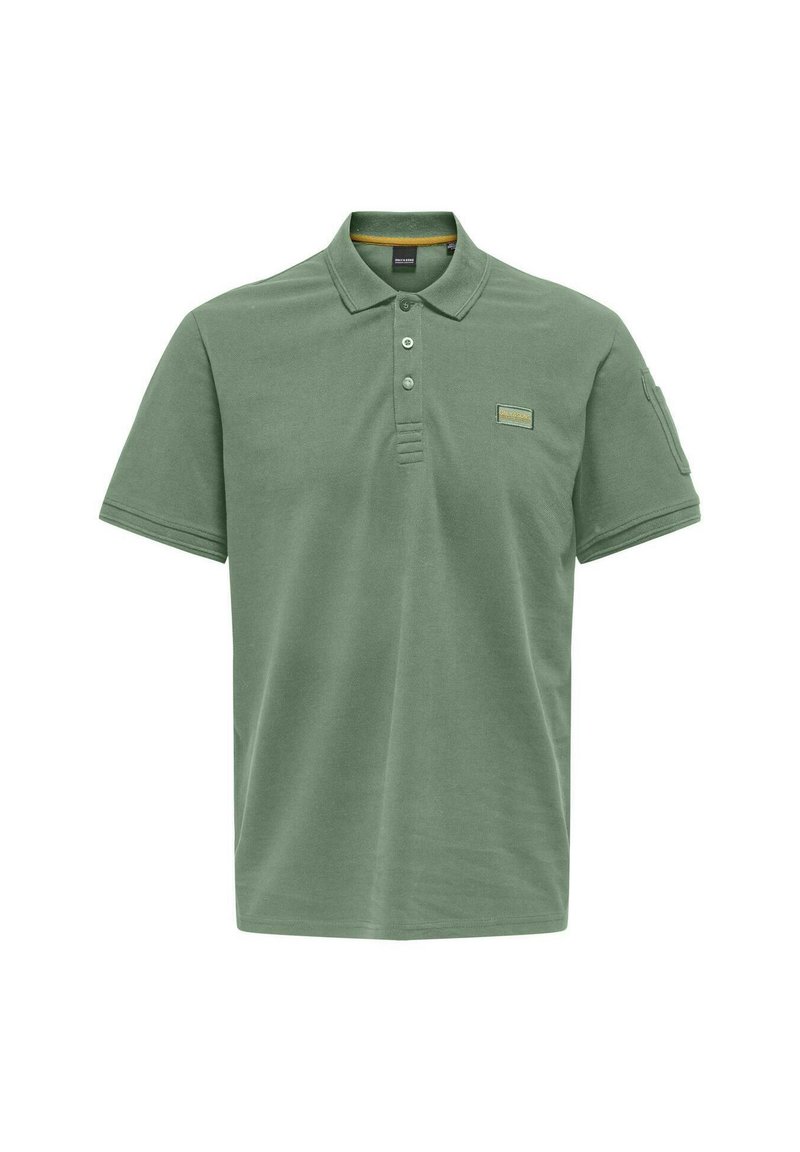Polo-Shirt aus gedämpftem grünen Baumwollstoff, mit Kragen, drei Knöpfen und einem gestickten Etikett auf der Brust. Kurzarm.