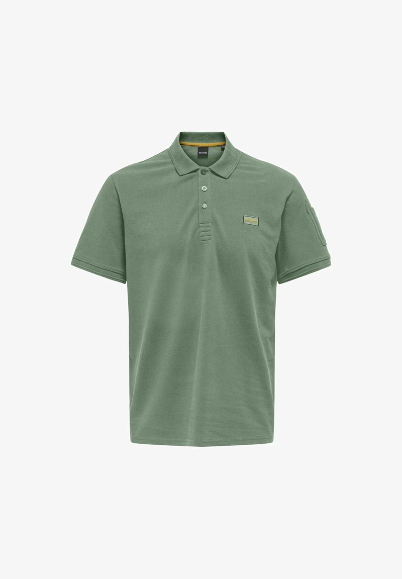 Polo shirt in muted green cotton, featuring a collared neck, three-button placket, and a stitched label on the chest. Short sleeves.