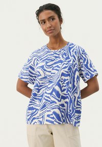 T-shirt à manches courtes, bleu et blanc à motif, avec une coupe ample, présentant des designs abstraits inspirés des zèbres et un col rond.