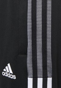 Black athletic apparel featuring three vertical white stripes along the side, made of a textured material with an Adidas logo in white.