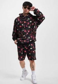 Black hoodie and shorts set featuring colorful palm tree and sunset patterns. Made from soft material with a relaxed fit. Multi-colored accents.
