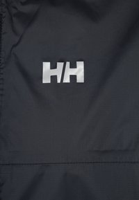 Tela negra con una superficie texturizada y un destacado logo plateado "HH" centrado. El material parece ligero y duradero.