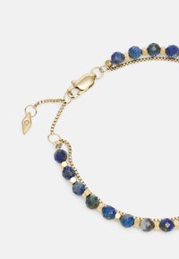 Gold-tone chain bracelet featuring round blue gemstones and hexagonal gold accents, with a lobster clasp and adjustable chain for length.
