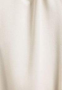 Beige textielstof met een subtiel patroon, met een zachte val en een gladde afwerking. Geschikt voor verschillende textieltoepassingen.