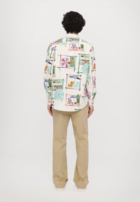 Trükitud pika varrukaga särk, millel on heledatooniline taust ja värvikad rannateemalised illustratsioonid; sobitatud beezide pükstega.