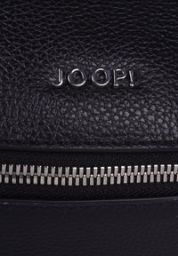 Borsa in pelle nera con superficie testurizzata e zip argentata. Il marchio "JOOP!" è impresso in argento sul davanti.