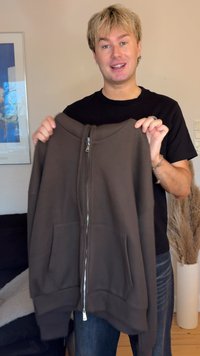 Brown zip-up hooded sweatshirt with ribbed texture, large front pockets, and silver zipper. Fabric appears soft and casual in design.