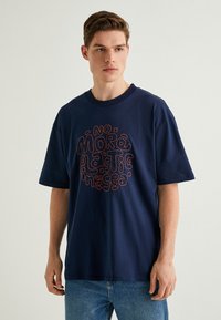 Mørkeblå kortærmet t-shirt i bomuld med et fremtrædende farverigt tekstdesign, der siger "Ikke mere plastik i havet." Standard pasform.