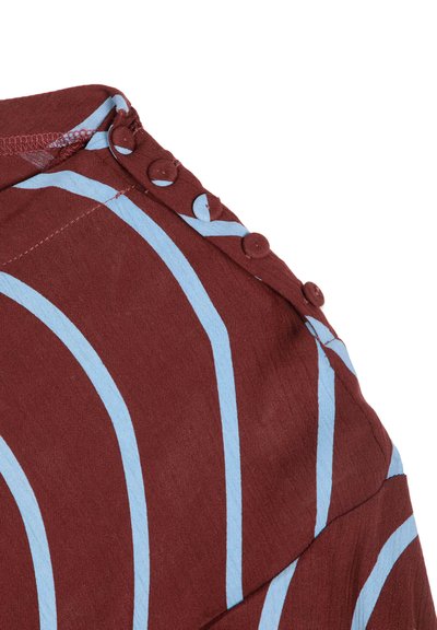 Tissu marron avec des rayures courbes bleu clair présentant une rangée de cinq boutons recouverts de tissu le long d'une couture.