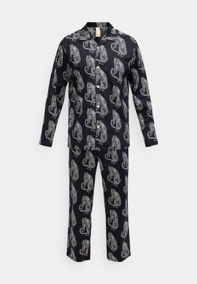 Tamsi medvilninė pižamos komplektas su balto tigro atspaudais. Viršus turi apykaklę, sagas ir ilgomis rankovėmis; kelnės laisvo kirpimo.