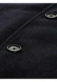 Tela de abrigo de lana azul marino con una textura suave; presenta dos botones negros con un diseño de cuatro agujeros en el centro y una costura plana en la parte delantera.