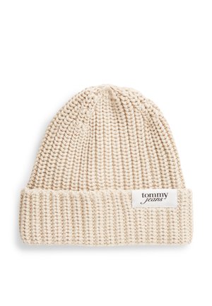 Bonnet beige en grosse maille avec bord replié et étiquette blanche rectangulaire portant la mention "tommy jeans" sur le devant du bord.