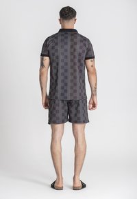Krátký rukáv polo tričko a šortky set s geometrickým vzorem v tmavých tónech, s pevným černým límečkem a elastickým pasem.