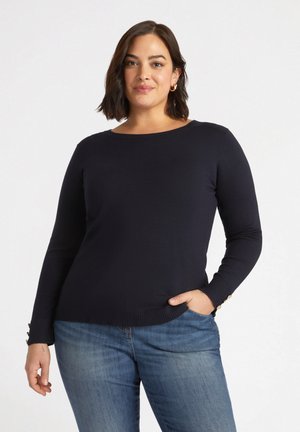 Maglione navy a maniche lunghe con scollatura rotonda. Polsini a coste con dettagli di bottoni. Tessuto morbido che si adatta al corpo, abbinato a jeans in denim.