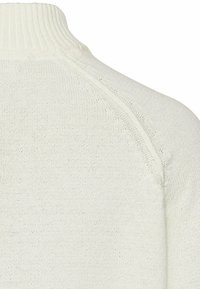 Weißer Strickpullover mit hohem Rippkragen, nahtlosen Schultern und einem strukturierten, lockeren Gewebemuster.