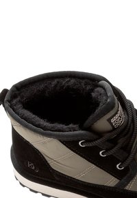 Svart och olivgrön ankelboot med en texturerad mocka- och nylonöverdel, foder i konstpäls och en vit gummisula med ett mönster för bättre grepp.