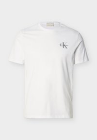 Λευκό βαμβακερό κοντομάνικο T-shirt με μικρό γκρι λογότυπο «Calvin Klein» στο αριστερό μέρος του στήθους, στρογγυλή λαιμόκοψη και κανονική εφαρμογή.