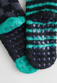 Calze pelose in blu scuro e teal, con motivo a strisce; dotate di punte in gomma testurizzate sui fondi per una presa migliore; tessuto confortevole.