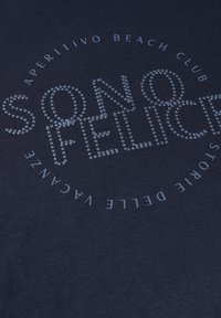 T-shirt bleu marine avec de lettres à pois qui dit « SONO FELICE » au centre, avec « APERITIVO BEACH CLUB » disposé en cercle autour.