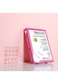Teaology vlekkenpleisters verpakking in roze met witte tekst. Bevat 32 doorzichtige, ronde hydrocolloïd pleisters. Belangrijke ingrediënten vermeld.