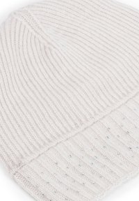 Biała dziana czapka z prążkowaną fakturą i ozdobnymi srebrnymi ćwiekami na podwiniętym mankiecie. Miękki materiał, lekka konstrukcja.