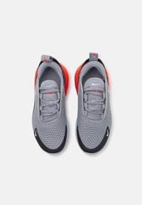 Pilki tinkliniai sportbačiai su raudonomis detalėmis, juodais padais ir elastingais raišteliais. Ant batų yra Nike logotipas ir kilpa kulne.