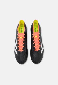 Zwarte voetbalschoenen met een gestructureerde afwerking, voorzien van neonroze veters, een felgele binnenkant en drie witte strepen aan de zijkanten.