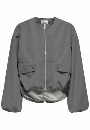 Sakjods pelēkā krāsā ar noapaļotu kakla izgriezumu, priekšējo rāvējslēdzēju un divām pogām aizdarītām kabatām. Gluda, viegla auduma struktūra ar spīdīgu oderi.