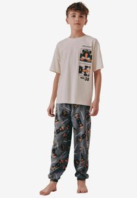 Hvid bomulds t-shirt med grafisk design med orange og sorte bilmotiver; grå pyjamabukser med gentagne bil- og logo-mønstre.
