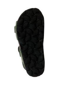 Suola di scarpa in gomma nera con un motivo a tratto ondulato e un bordo superiore modellato verde, caratterizzato da una superficie testurizzata per una migliore presa.