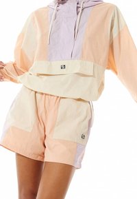Kleurblok pullover in pastelperzik, lavendel en roomkleur. Met een capuchon, een voork pocket en een verstelbaar koord. Gecombineerd met bijpassende shorts.