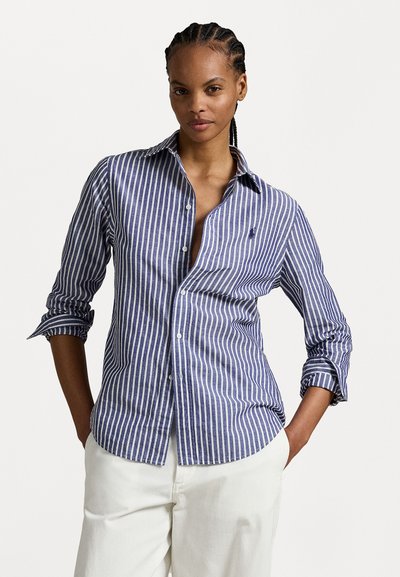 Chemise à boutons bleu et blanche à rayures, avec des manches longues et un col décontracté, dotée d'une poche poitrine et d'un ourlet arrondi.