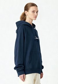 Sweat à capuche bleu marine avec une poche sur le devant, une capuche à cordon et le texte blanc "I don't" sur la poitrine. Tissu doux avec une coupe décontractée.