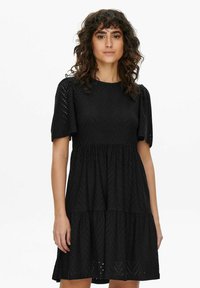 Black short-sleeve dress featuring textured eyelet fabric, a round neckline, and a tiered skirt design. Lightweight and breathable material.