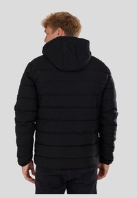 Chaqueta negra acolchada con capucha, con un patrón acolchado y puños elásticos. Textura suave, diseño ligero ideal para el clima frío.