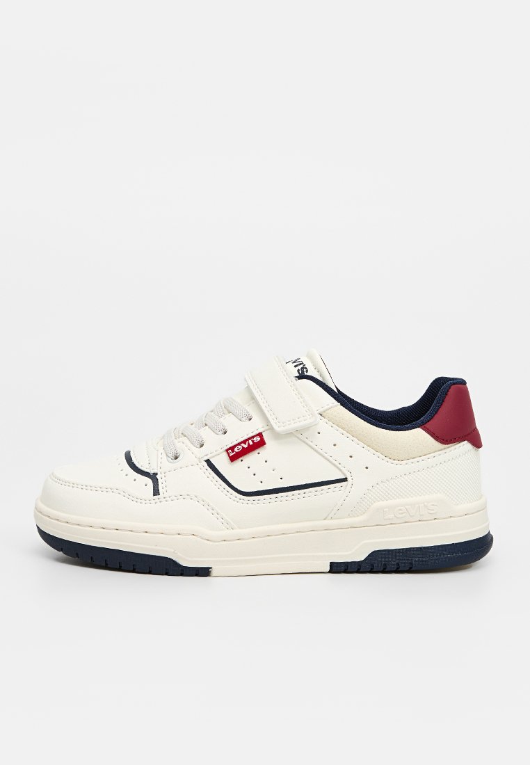 Zapatilla baja blanca de Levi's con acentos en azul marino, detalle rojo en el talón, correa de Velcro y cierre de cordones sobre un fondo claro y liso.