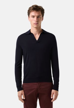 Marineblauer Strickpullover mit V-Ausschnitt und langen Ärmeln. Bietet eine weiche Textur und eine taillierte Silhouette, kombiniert mit bordeauxfarbenen Hosen.
