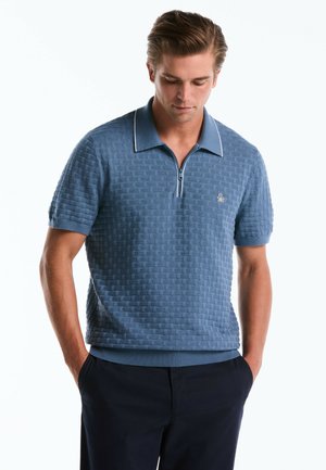 Lichtblauwe polo met een gestructureerd geweven patroon, korte mouwen, ritsluiting en een contrasterende kraag in een effen lichtblauw.