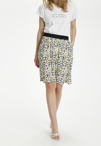 Bloemenrok met een zwarte basis, witte en gele bloemen, elastische tailleband en een losse, knie-lange snit, gecombineerd met een wit grafisch T-shirt.