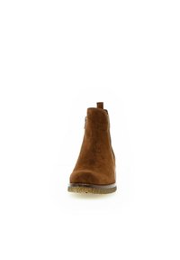 Stivaletto in suede marrone con finitura liscia, punta arrotondata e zip sul retro per una facile calzata. Presenta una suola in gomma naturale.