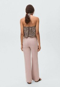 Blommig mönstrad bandeau-top kombinerad med högmidjade, ljusrosa vida byxor. Toppen har en volangdesign, medan byxorna har bakfickor.