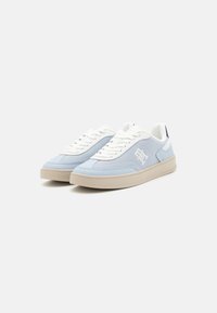 Baskets bleu clair avec accents blancs, tige en maille texturée, lacets plats et semelle en caoutchouc beige. Comprend un logo sur le côté.