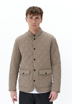 Chaqueta acolchada beige con un alto cuello, botones negros, dos bolsillos frontales y una textura suave. Diseño minimalista y corte ajustado.