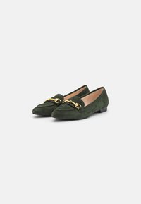Scarpe flat in suede verde con punta a punta, caratterizzate da un accento in catena color oro sulla parte anteriore e un tacco basso. Fodera interna liscia.