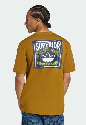 Brown cotton t-shirt featuring a large graphic on the back with "SUPERIOR SPORTING GOODS" and an Adidas logo in white and green.