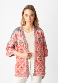 Spalvota raštuota kimono striukė raudonos ir mėlynos spalvų, pasižyminti laisvu siluetu, plačiomis rankovėmis ir dekoratyviais mygtukais priekyje.