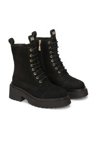 Stivaletti neri in suede con tacco largo, dotati di occhielli in tonalità oro, lacci e una cerniera laterale per indossarli facilmente.