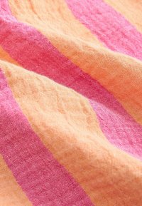 Tela a rayas con colores alternos de naranja claro y rosa. La textura parece suave con un patrón ligeramente tejido, mostrando una superficie arrugada.