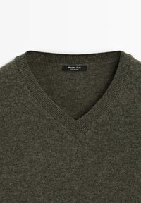 Pull en maille gris vert foncé à col en V avec col côtelé et étiquette "Massimo Dutti" à l'intérieur de l'encolure.
