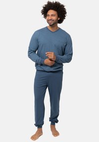 Sininen oleskelusetti, joka koostuu kuvioidusta pitkähihaisesta paidasta ja yksivärisistä joustavista housuista, joissa on kapenevat lahkeet, valmistettu pehmeästä ja mukavasta kankaasta.